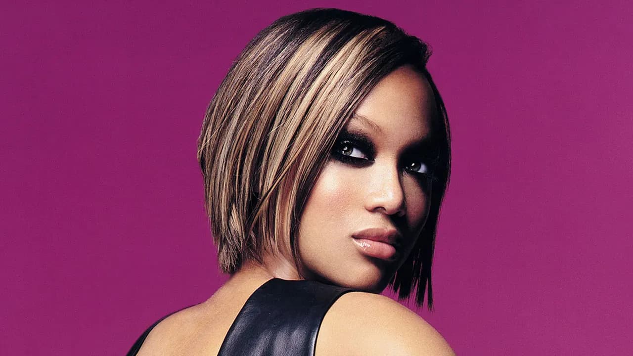 Tyra Banks striking a powerful pose during a photoshoot on America’s Next Top Model set